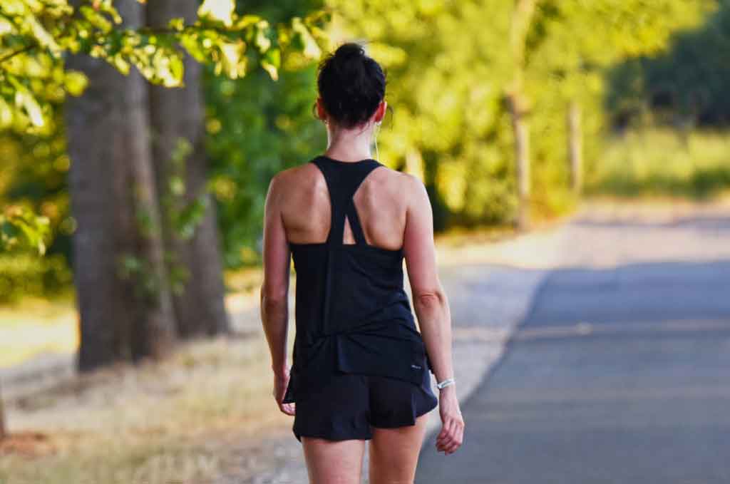 Girl, in running clothes, walking down a country road. Photo by Pixabay, MabelAmber.