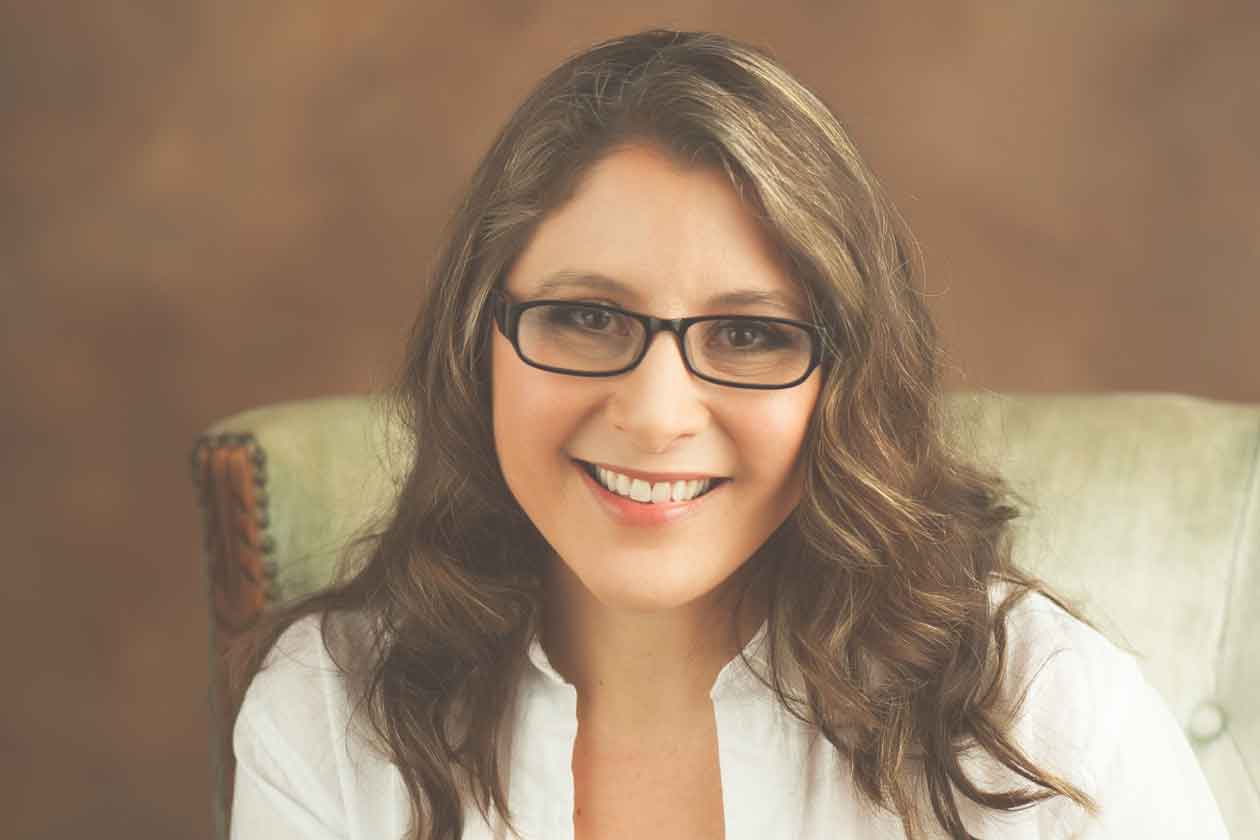 Author Crystal Flower smiling in a white top with black glasses